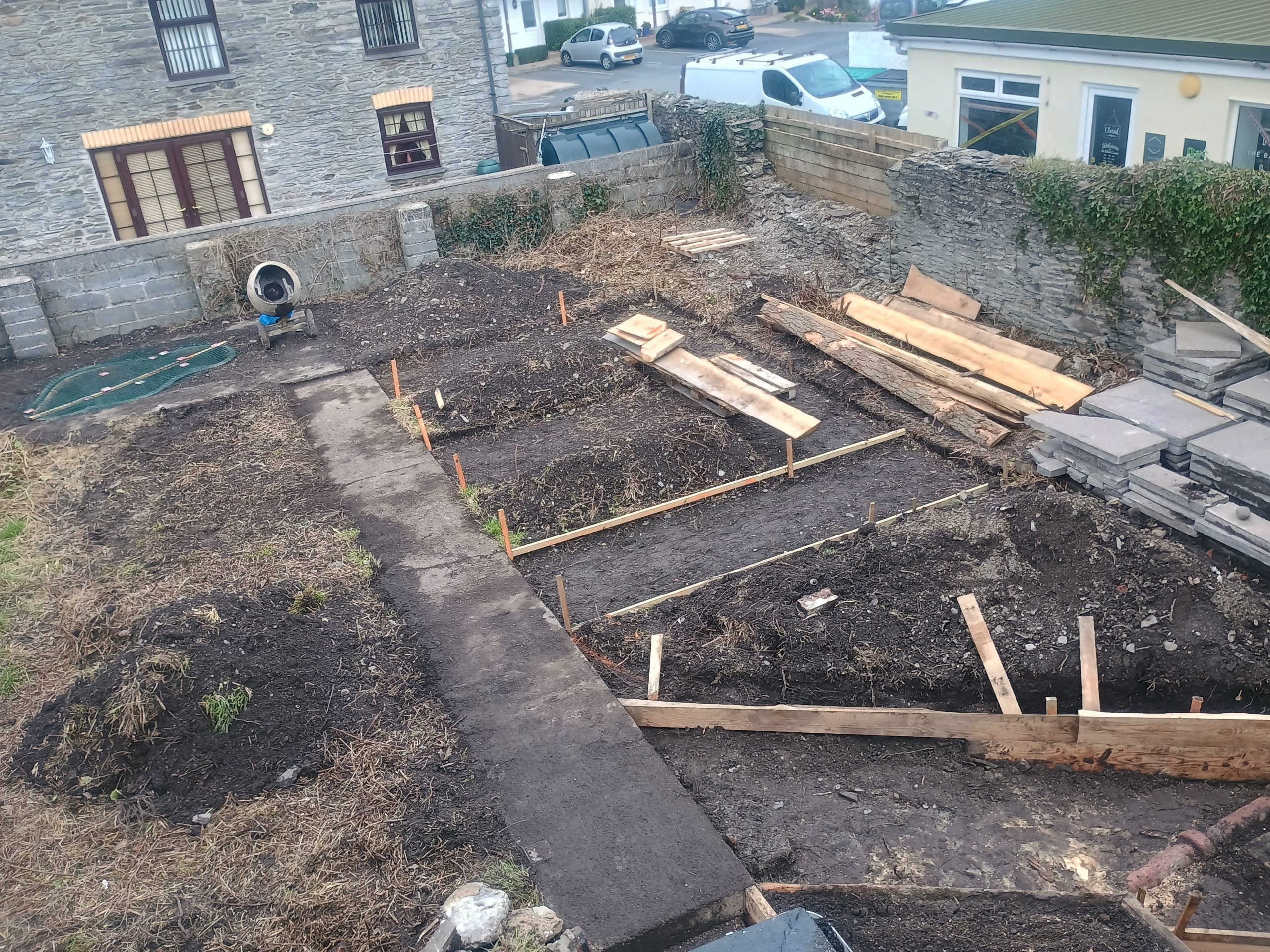 A garden in a midst of major ground works. There are pathways, a pond and the beginning of some raised beds.